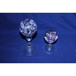 Two Victorian ornamental glass wig stands, each topped with a sulphide paperweight, (taller h21cm,