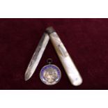 A hallmarked silver bladed pen knife with MOP decoration and a hallmarked silver and enamel pendant