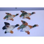 Four assorted ceramic ducks in flight (one with chip to beak)
