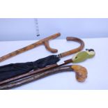 A selection of walking sticks and a vintage wooden handle umbrella, shipping unavailable
