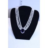 A simulated pearl necklace with blue stone pendant