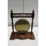 An Oriental brass gong on wooden stand.