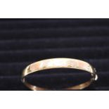 A solid 18ct gold bangle with a two tone gold leaf decoration. 14.42 grams.