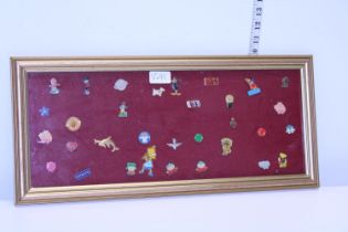 A framed and glazed selection of collectable pin badges
