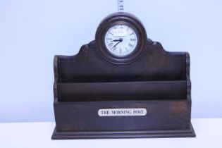 A wooden newspaper rack and clock combination