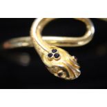 A solid 18ct gold bangle in the form of a serpent. With sapphire & rubies. 16.84 grams.