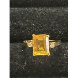 A 18ct gold ring with a large central yellow citrine flank by two small brilliant cut diamonds. GW