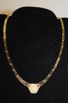 A quality 18ct gold necklace in greek key design. With a 18ct gold coin pendant set with four