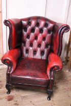 A vintage chesterfield leather wingback armchair in oxblood red. In good condition with general ware