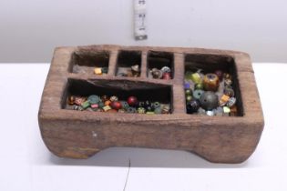 A antique Tibetan wooden spice box with contents of Oriental beads