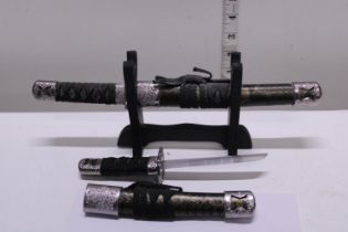 Two miniature samurai swords on stand
