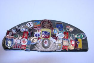 A Russian military cap with a large selection of enamelled badges