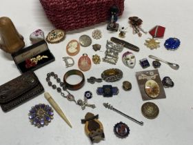 A basket of assorted collectibles including brooches