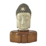 Kopf eines Buddha. Gesenkte Augenlider. Lange Ohren. Gelockte Frisur mit Urna aus Jade. Teils bemal