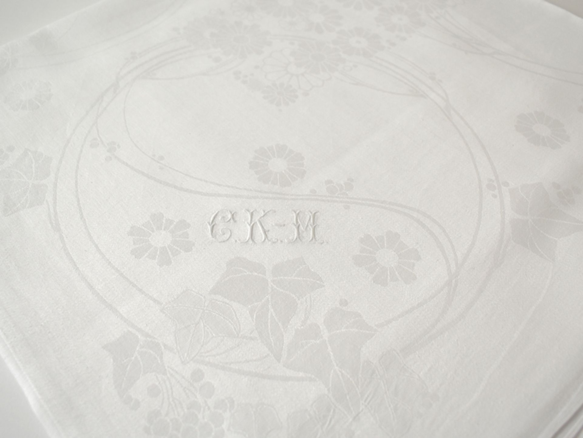 Feines Jugendstil-Tafeltuch mit stilisierten Blumen und Monogramm "CKM". Feiner weißer Seidenleinen