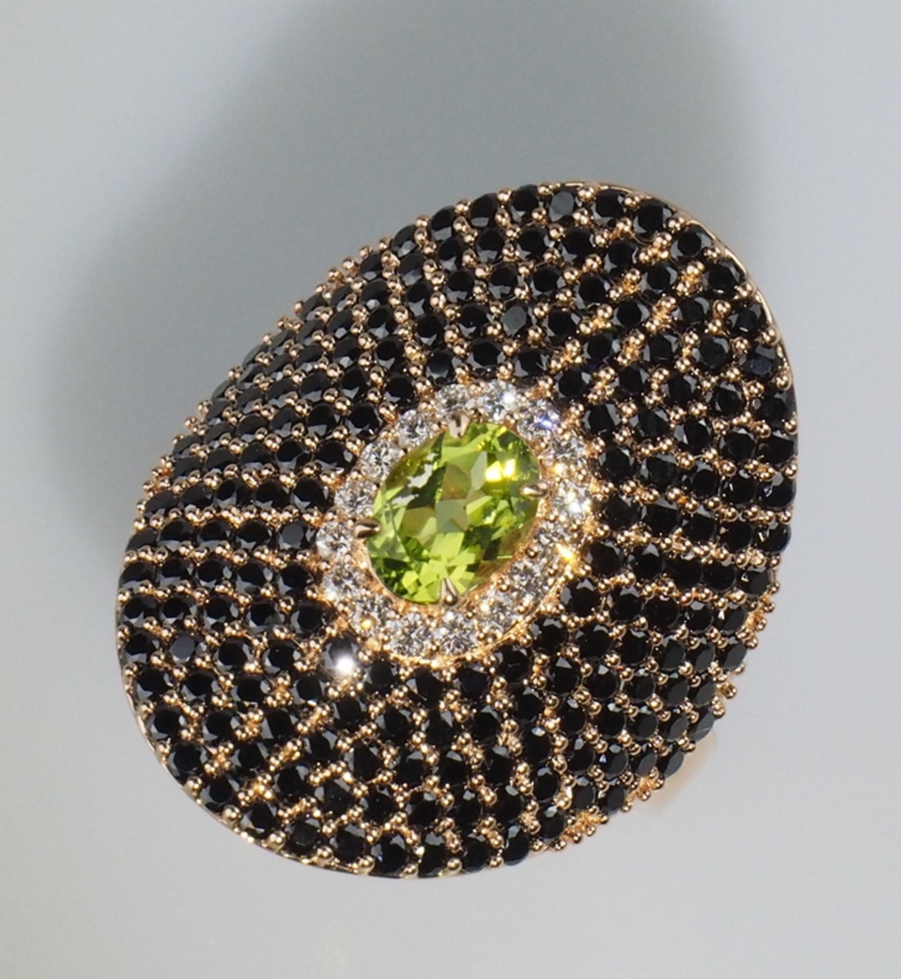 Eleganter Cocktailring. Mittig Peridot, entouriert von 0,24 ct. Brillanten. Auf gewölbtem Grund sch