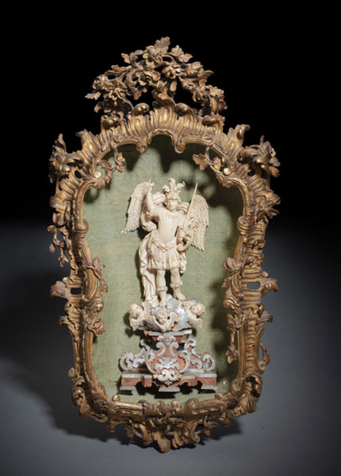 A FINELY CARVED IVORY FIGURE OF ST. MICHAEL IN A DECORATIVE FRAME