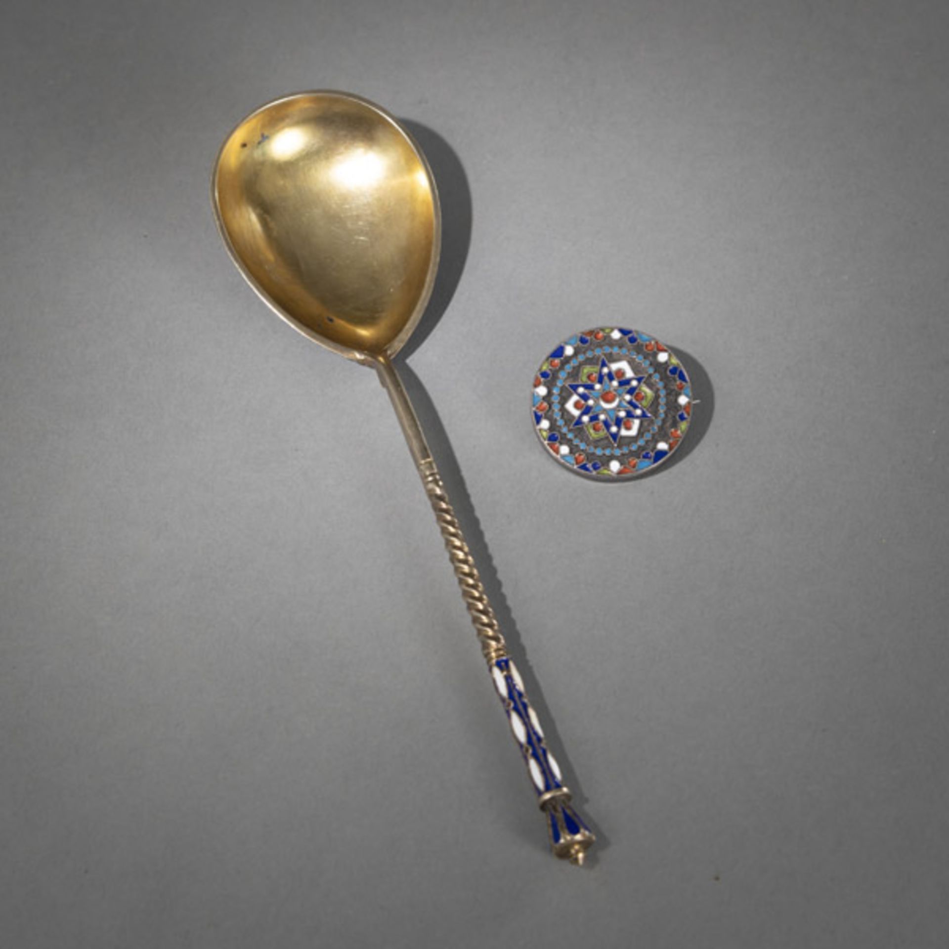 AN ENAMELLED SILVER SPOON AND A CLOTHING BUTTON AS BROOCH