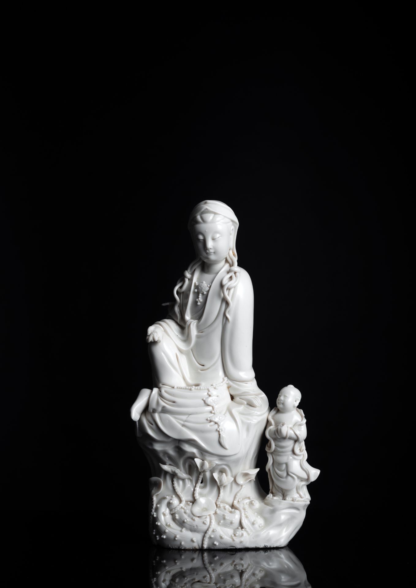 A DEHUA MODEL OF SEATED GUANYIN ON A ROCK WITH ADORANT