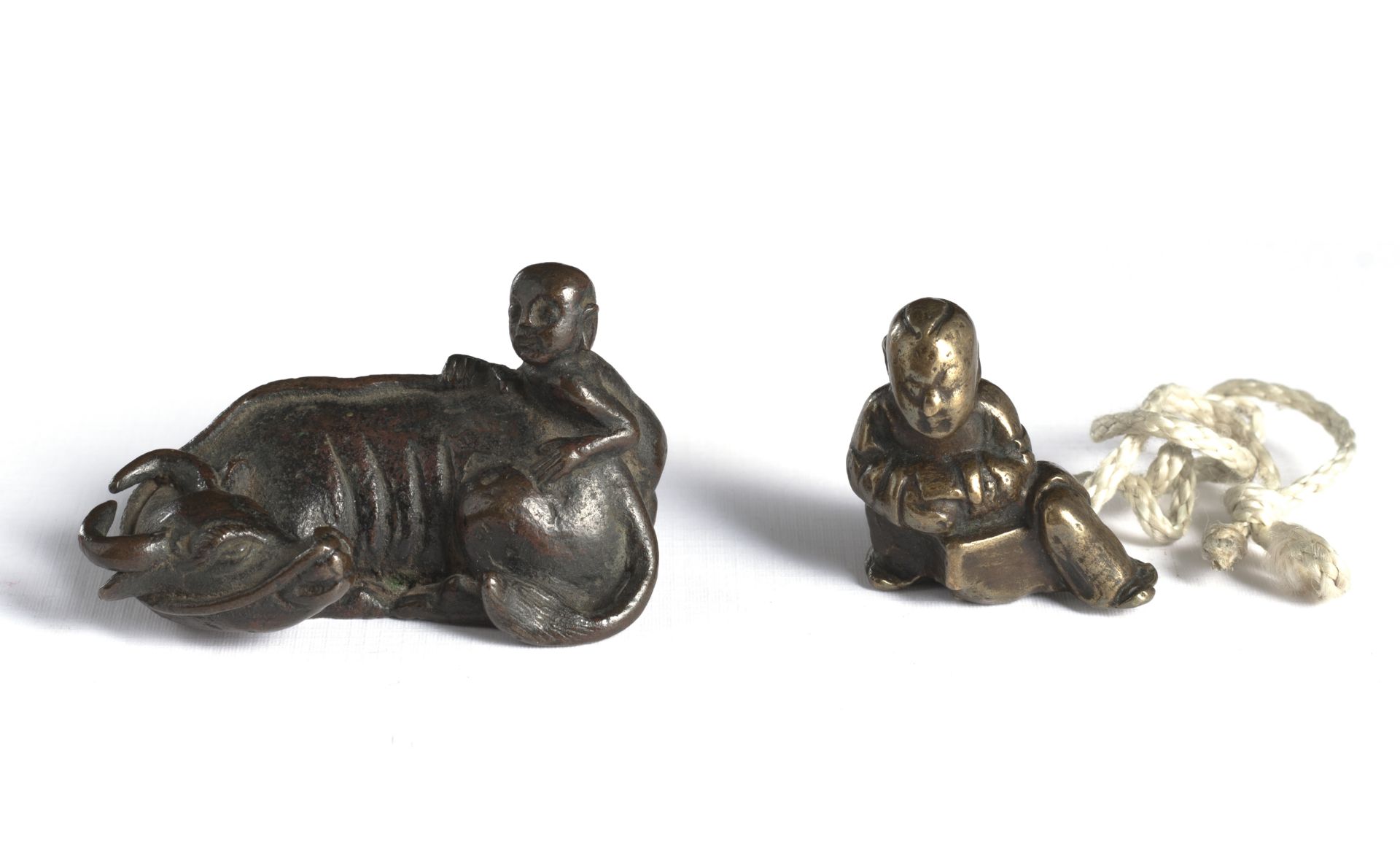 TWO SMALL BRONZES AS NETSUKE: A YOUNG BOY WITH BUFFALO AND A RESTING BOY