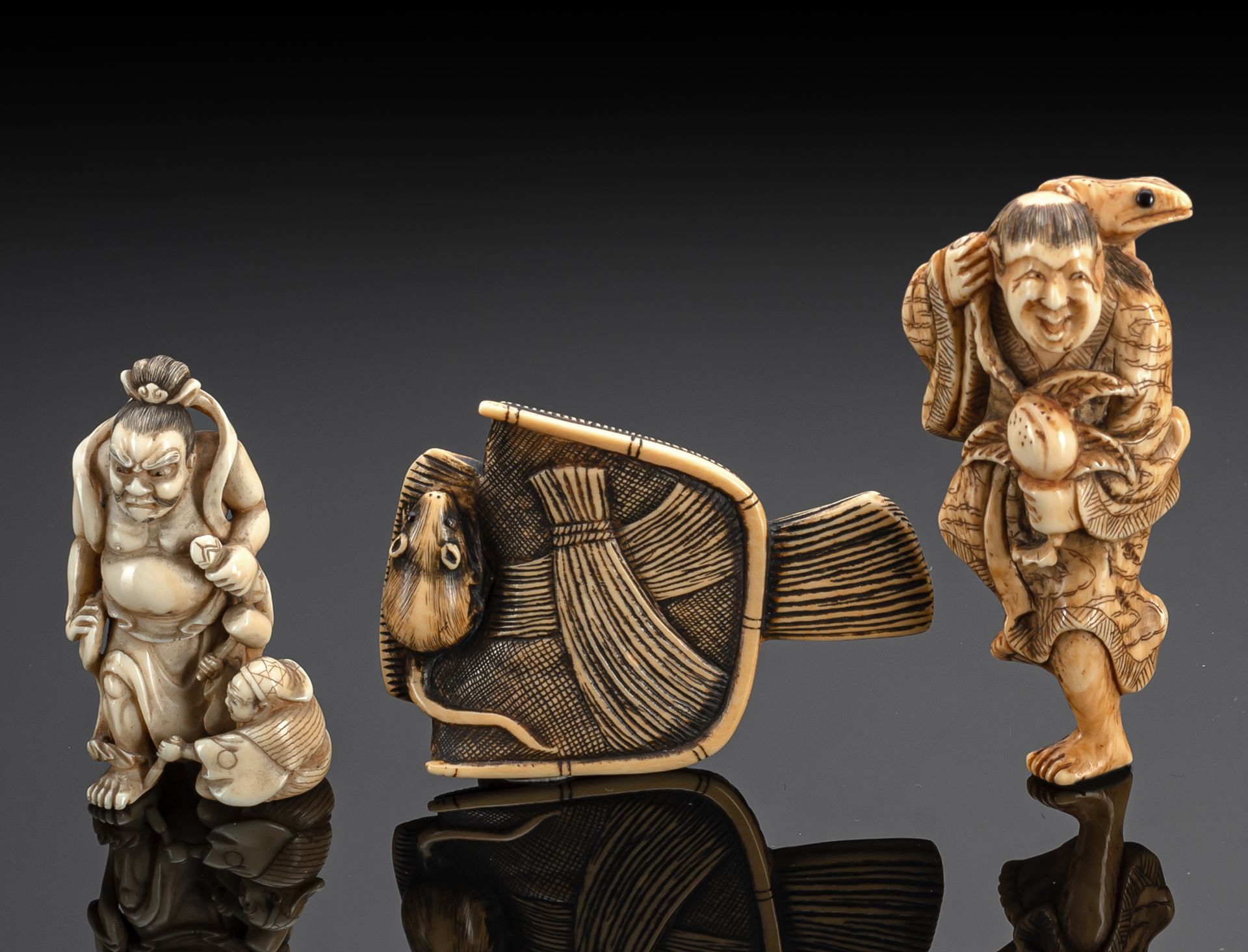 THREE CARVED IVORY NETSUKE OF GAMA SENNIN, DAIKOKU WORKING ON A NIO STATUE AND A RAT ON A BASKET