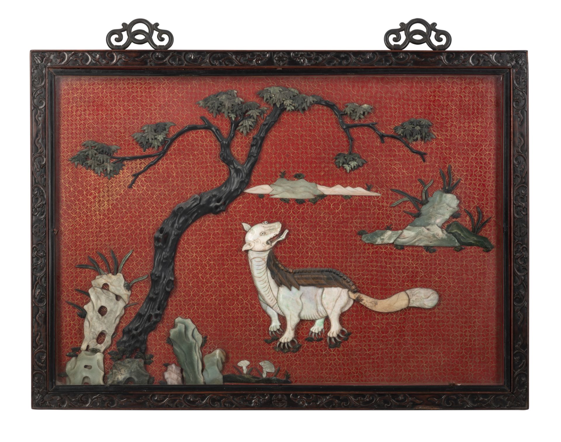 A LARGE CINNABAR-LACQUER-GROUND JADE- AND STONE-INLAID MYTHICAL BEAST PANEL IN FINELY CARVED FRAME