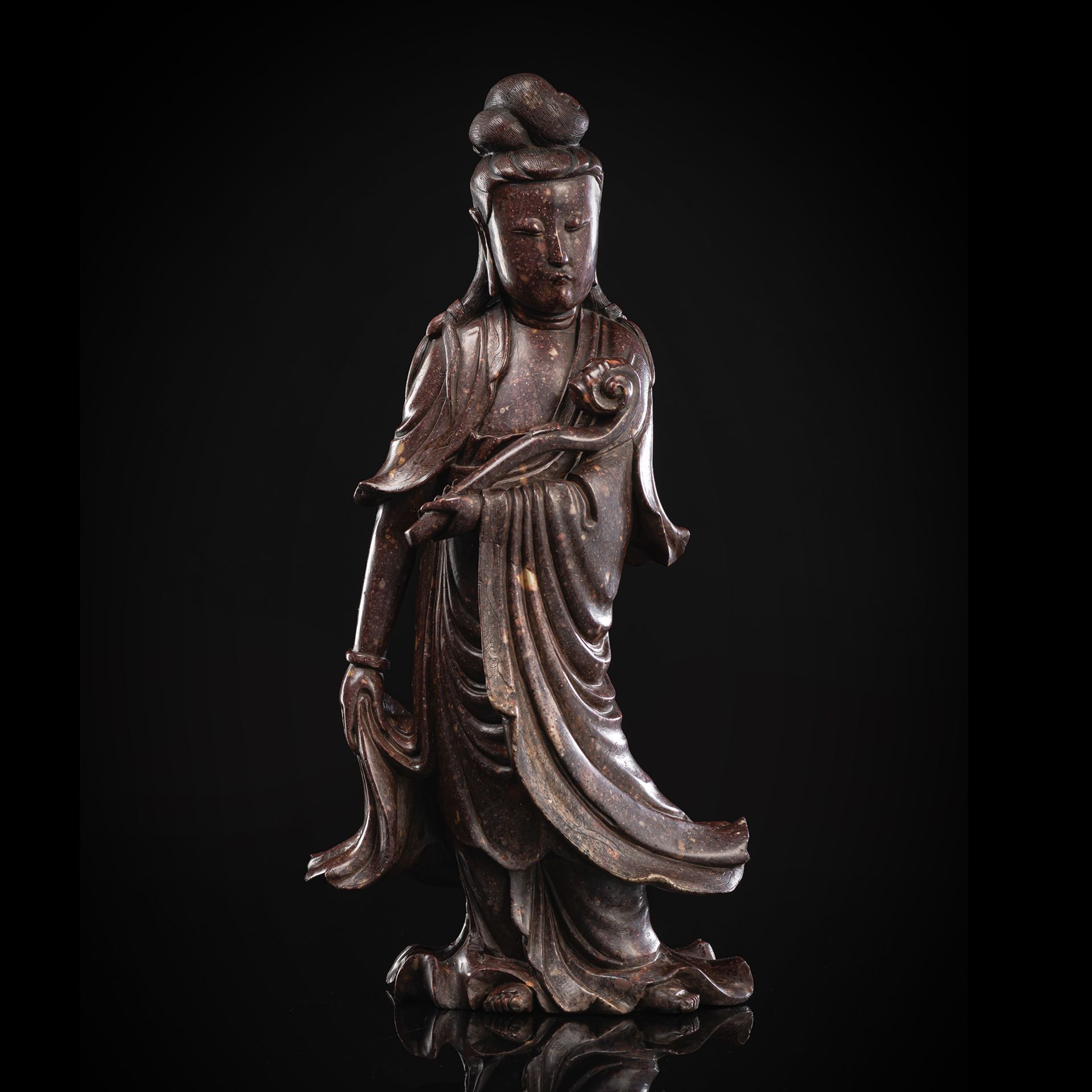 A CARVED REDDISH-BROWN CARVED SOAPSTONE MODEL OF STANDING GUANYIN WITH SCEPTER