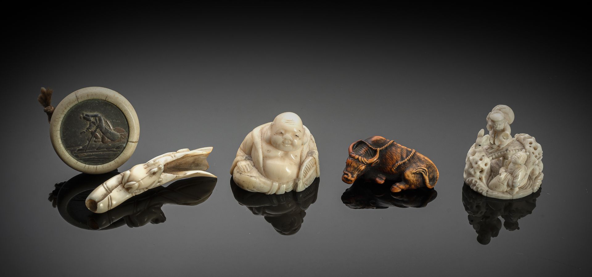 FOUR CARVED IVORY NETSUKE AND A KAGAMIBUTA: HOTEI, FROG ON LOTUS LEAF, RECLINING OX , EBISU RIDING