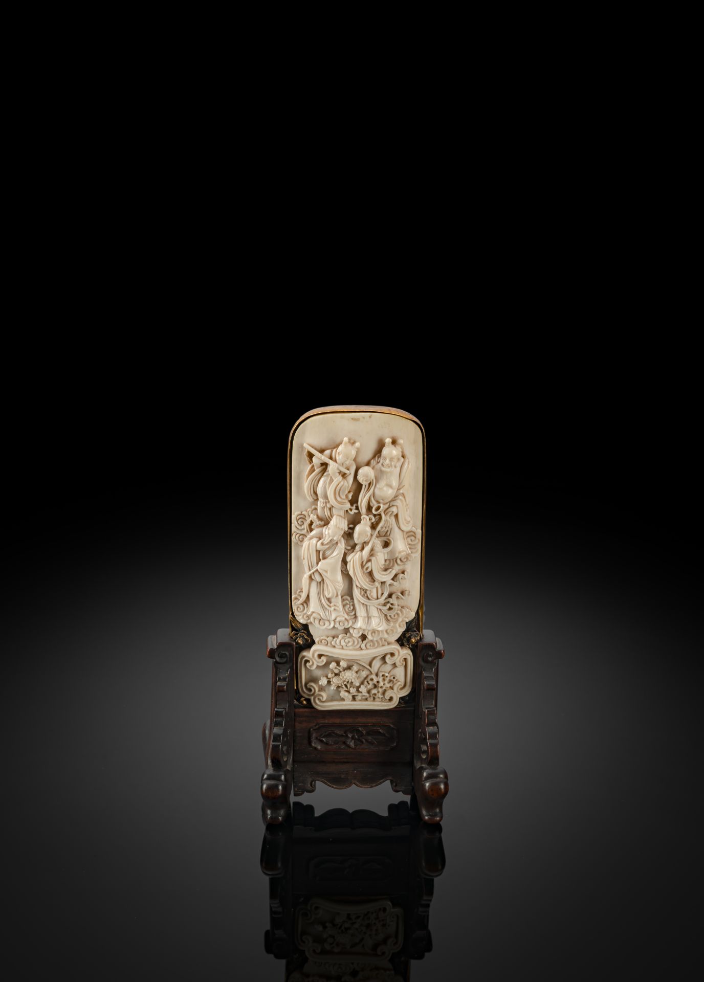 A FINE CARVED IVORY PANEL WITH GILT MOUNTS, MOUNTED AS SMALL TABLE SCREEN WITH WOOD STAND