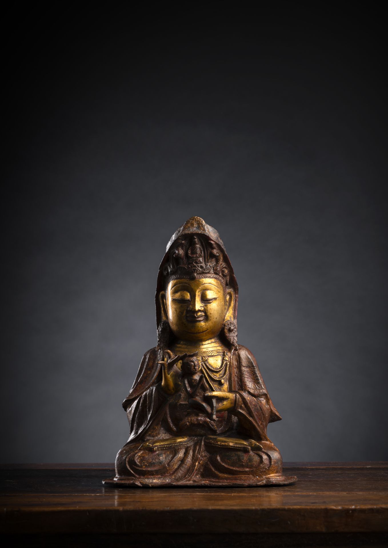 A PART-GILR´T AND GILT-LACQUERED BRONZE FIGURE OF SEATED GUANYIN HOLDING A BOY
