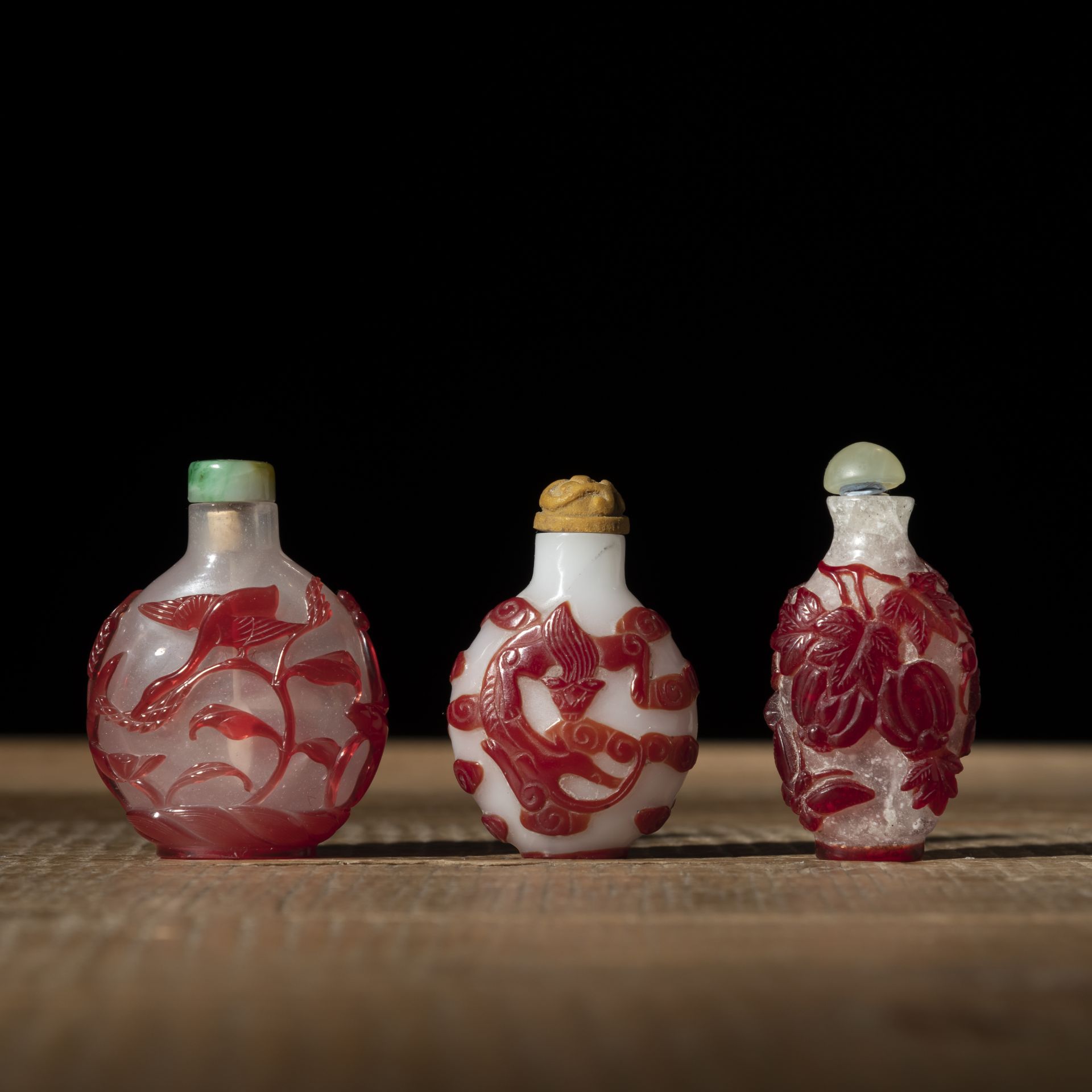 THREE PEKING GLASS SNUFF BOTTLES WITH RED OVERLAY DEPICTING WILD GEESE, CHILONG, PHOENIX AND MELON