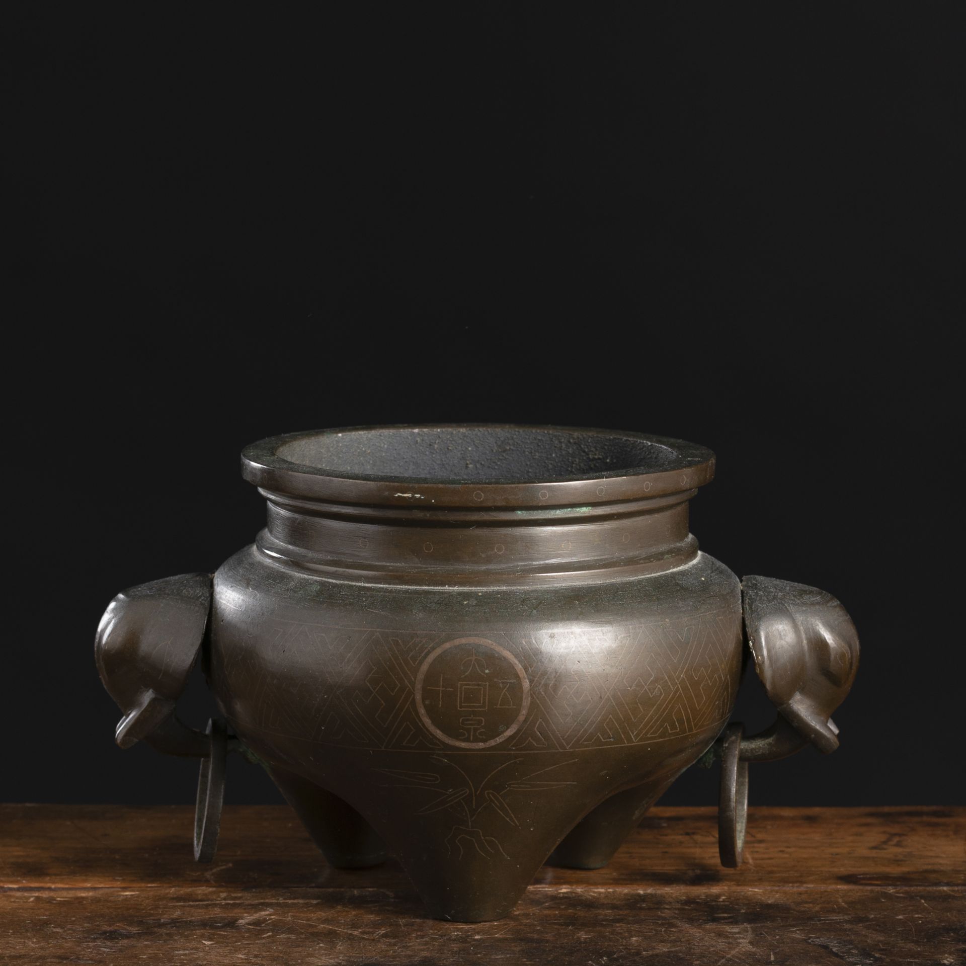 A TRIPOD BRONZE CENSER WITH SILVER WIRE INLAYS AND TWO ELEPHANT HEAD RING HANDLES