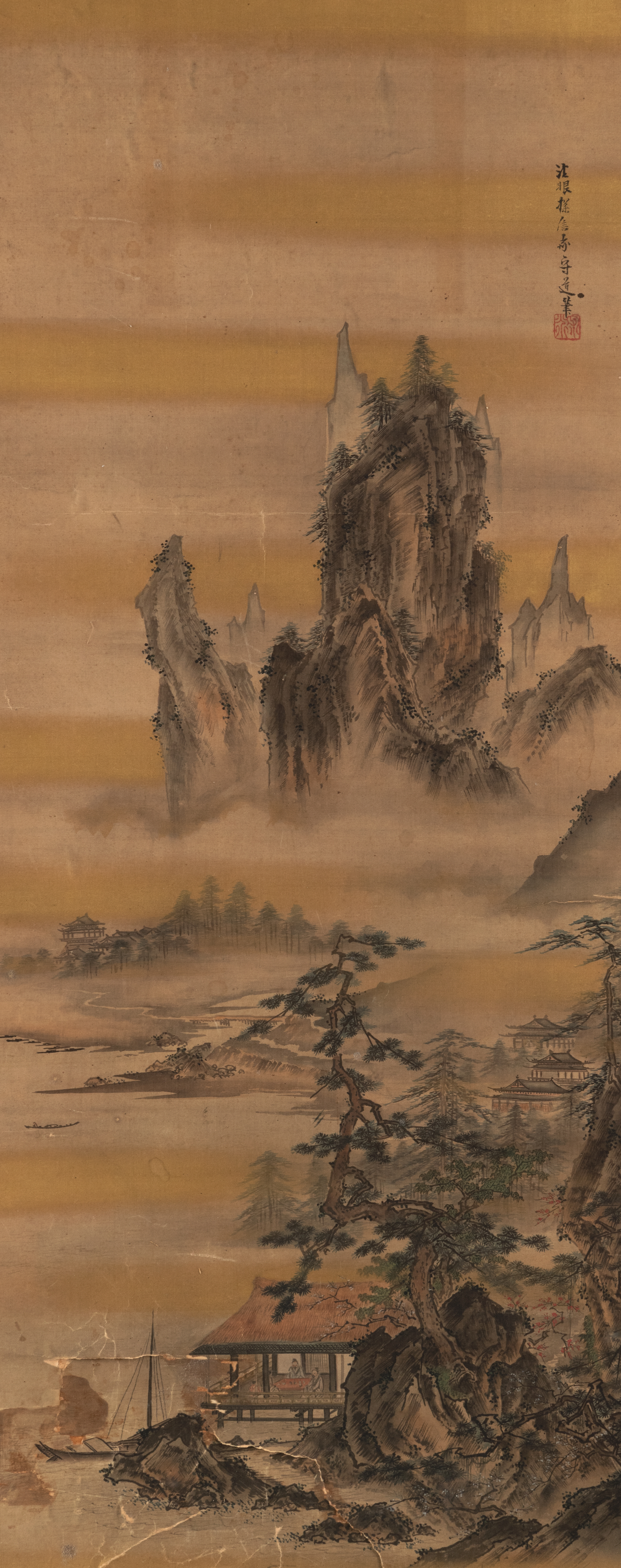 A HANGING SCROLL DEPICTING A LANDSCAPE WITH A SCHOLAR'S SUDIO AFTER KANO TANSHIN. INK AND COLORS ON
