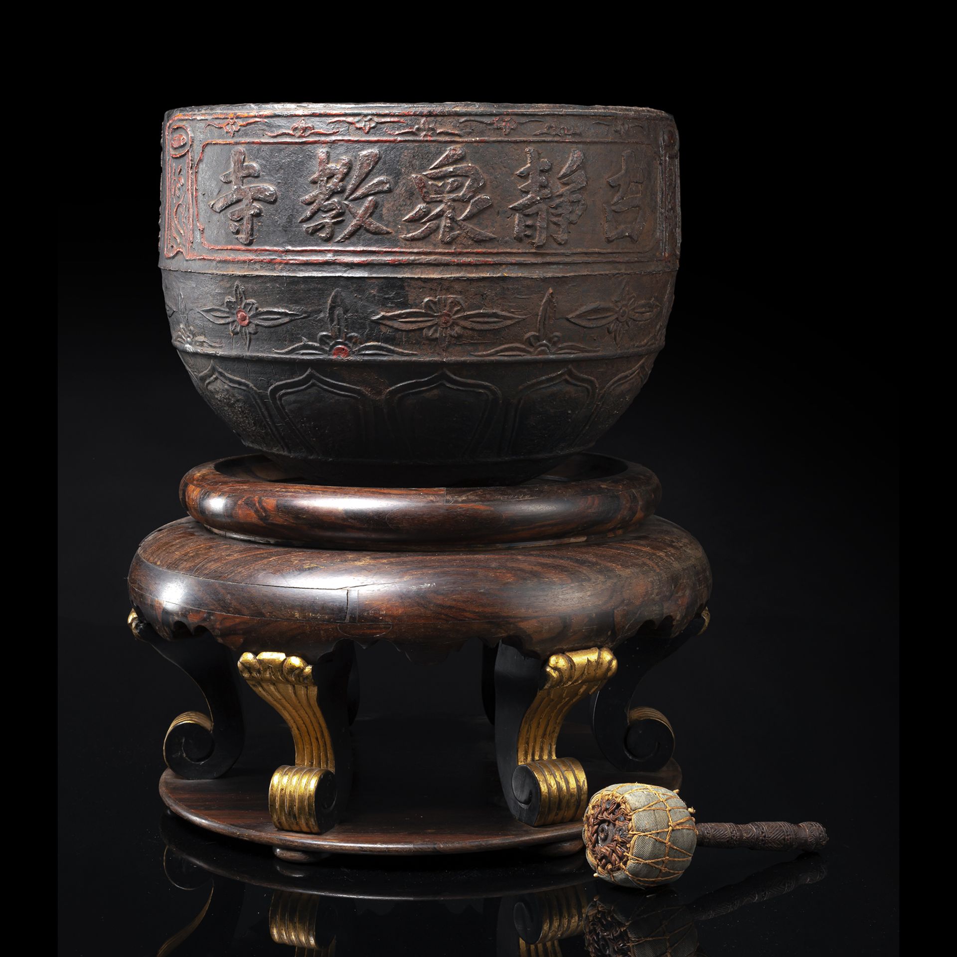 A LARGE CAST IRON SINGING BOWL WITH A MALLET ON WOOD STAND