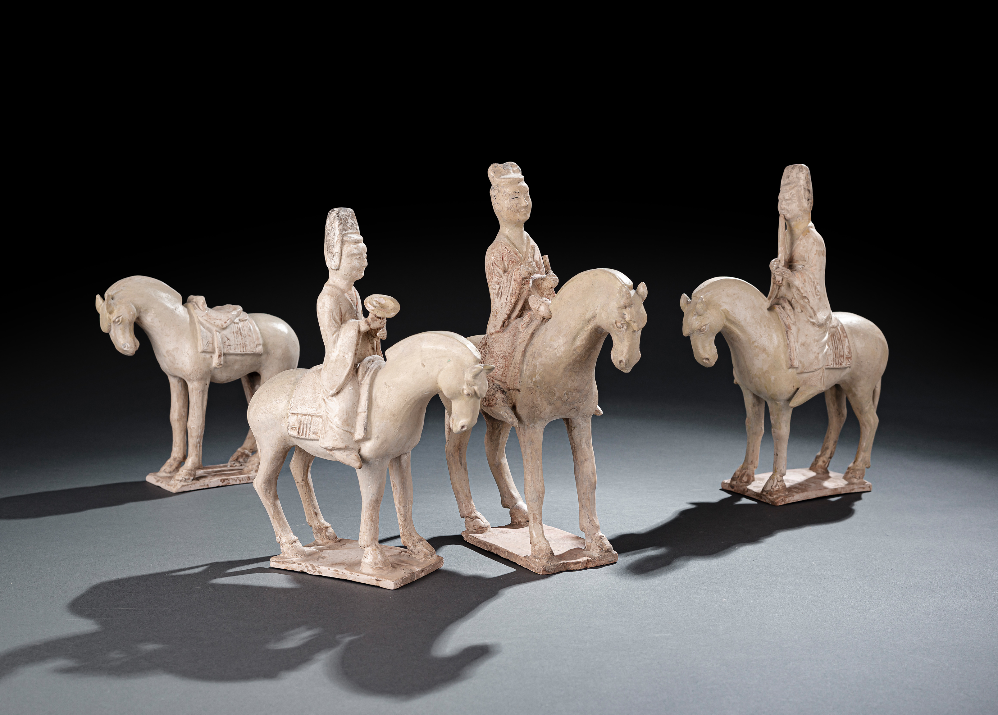 A GROUP OF FOUR STRAW-GLAZED EARTHENWARE HORSES AND RIDERS AND A HORSE