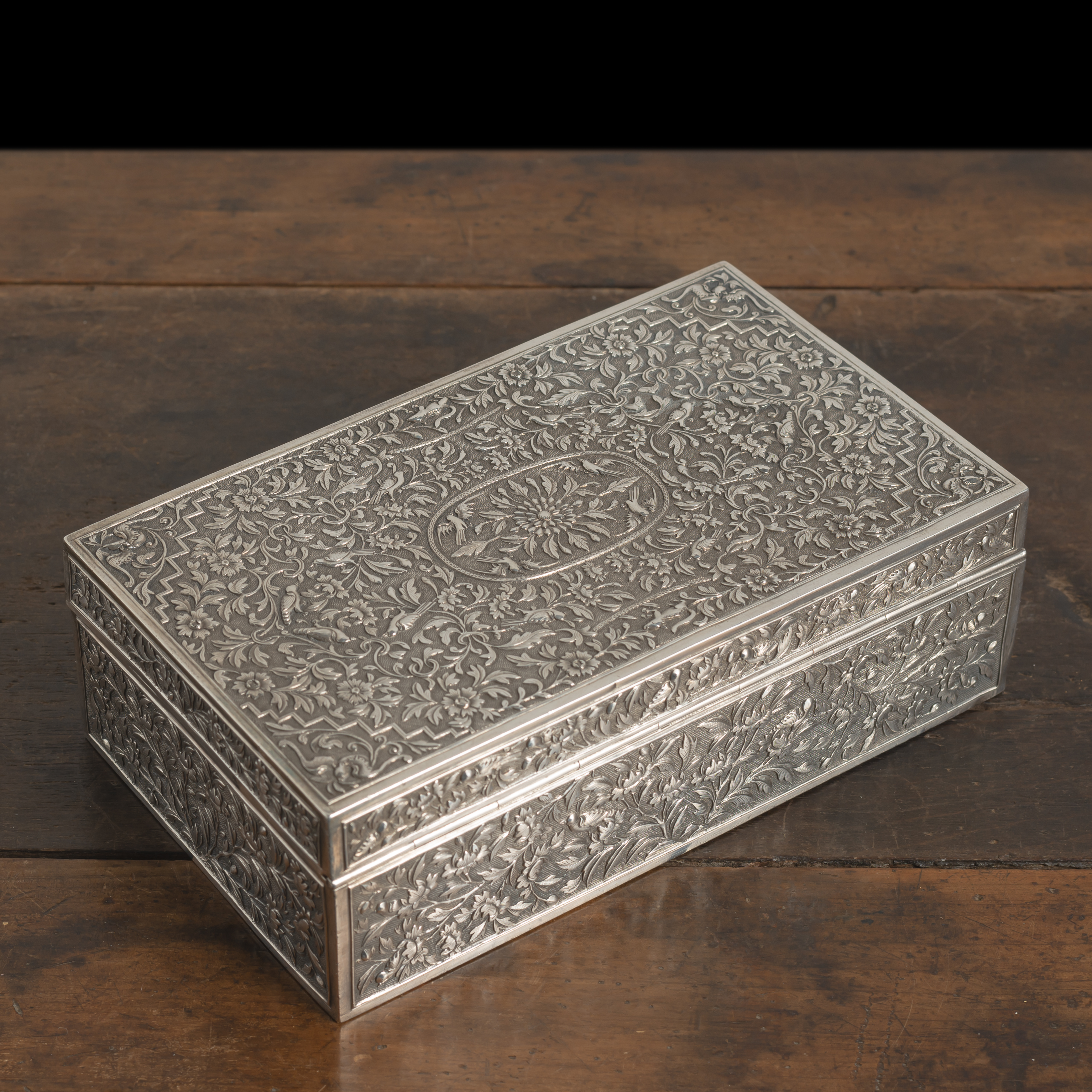 A RECTANGULAR HINGED FLORAL RELIEF SILVER BOX