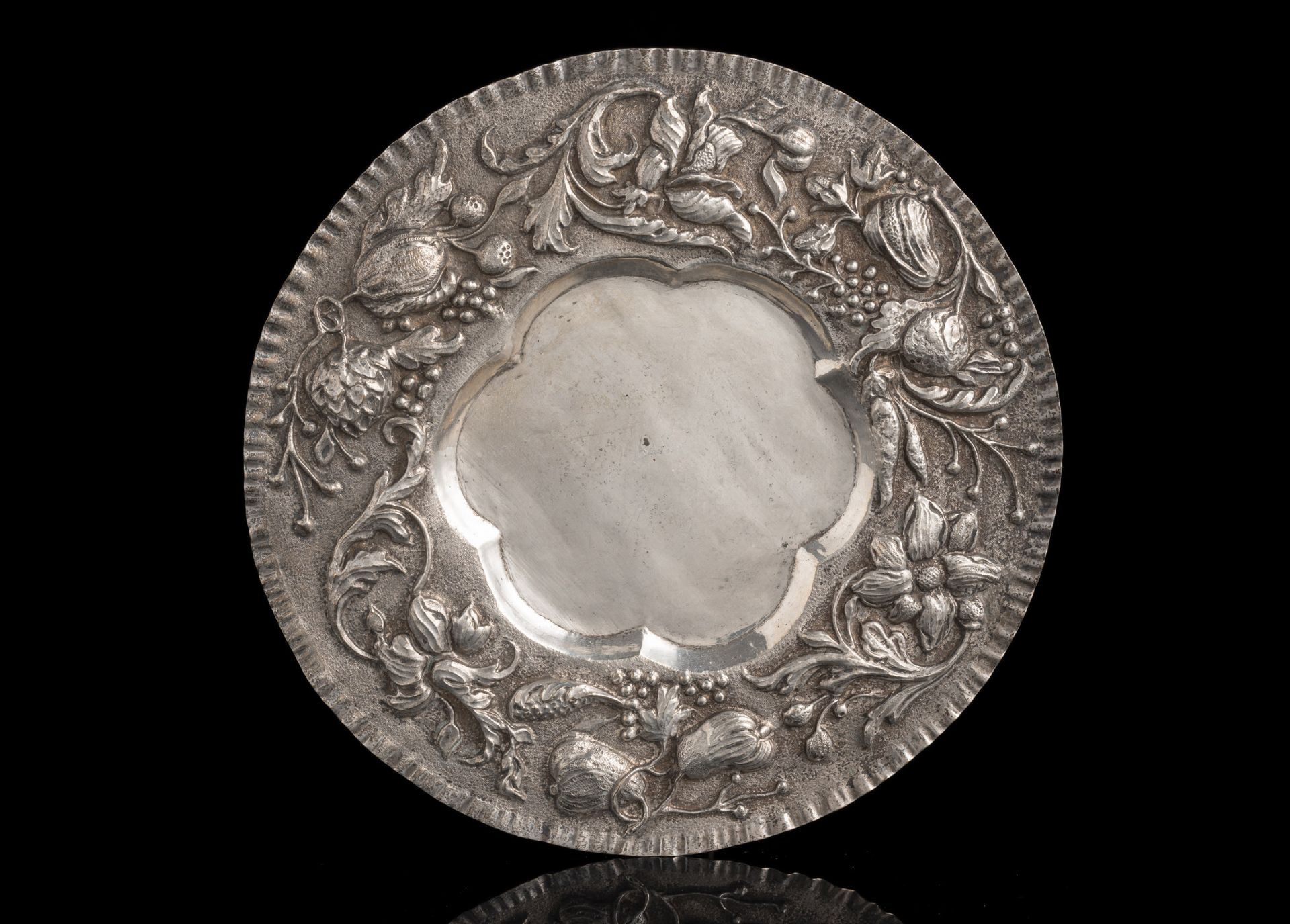 A SILVER ROUND DISH WITH FRUIT DECOR