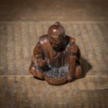 A CARVED WOOD NETSUKE OF A PEASANT MAN SELLING EGGS