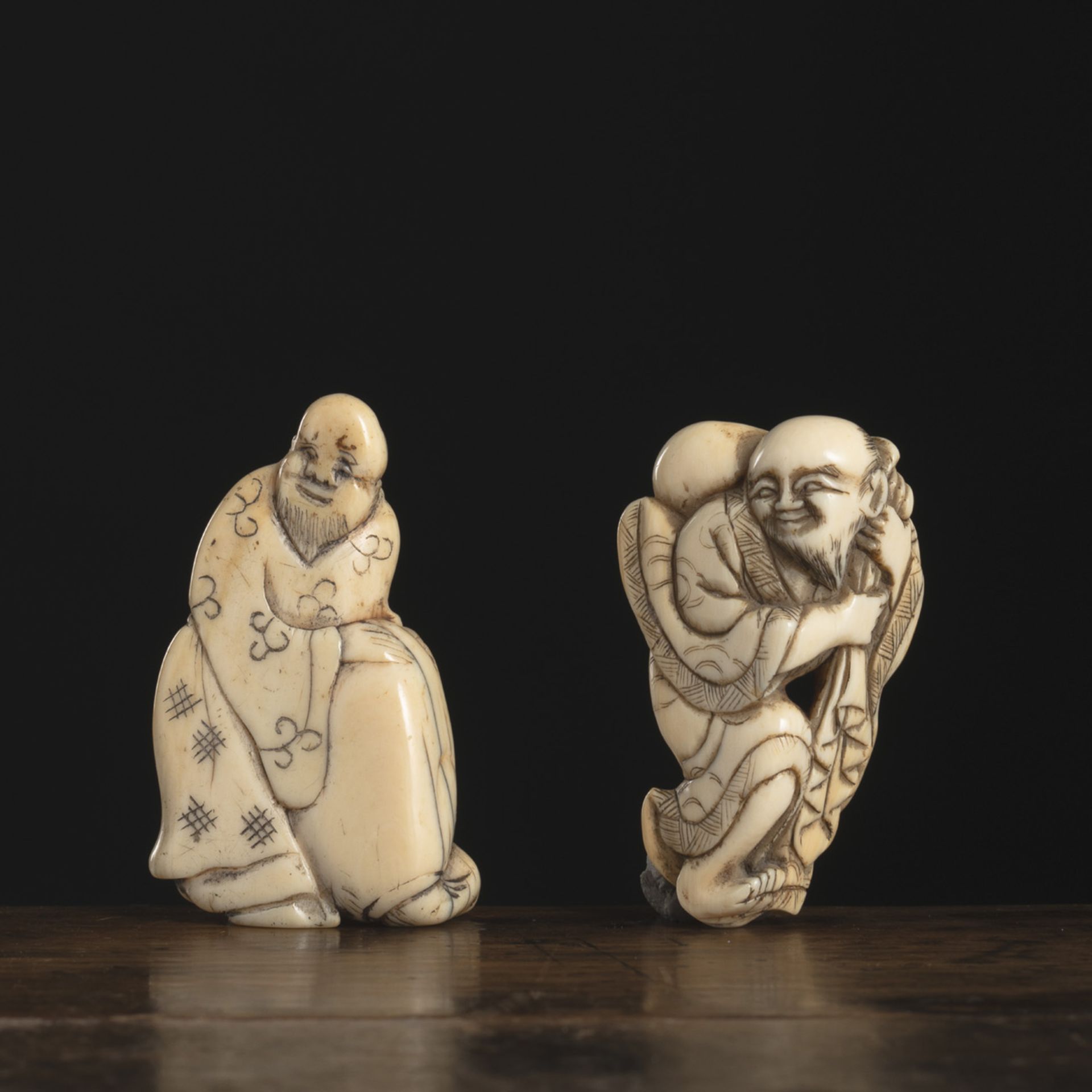 TWO IVORY NETSUKE: SENNIN OR HOTEI WITH A BAG ON HIS SHOULDER AND STANDING CHINESE WITH A LARGE BAG