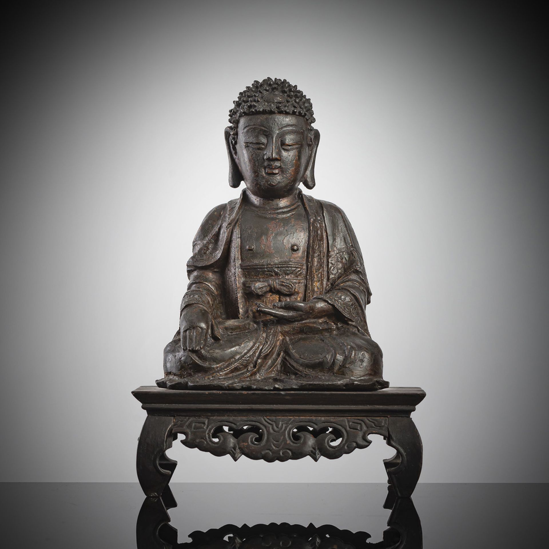 A BRONZE FIGURE OF SEATED BUDDHA ON A LATER WOOD STAND