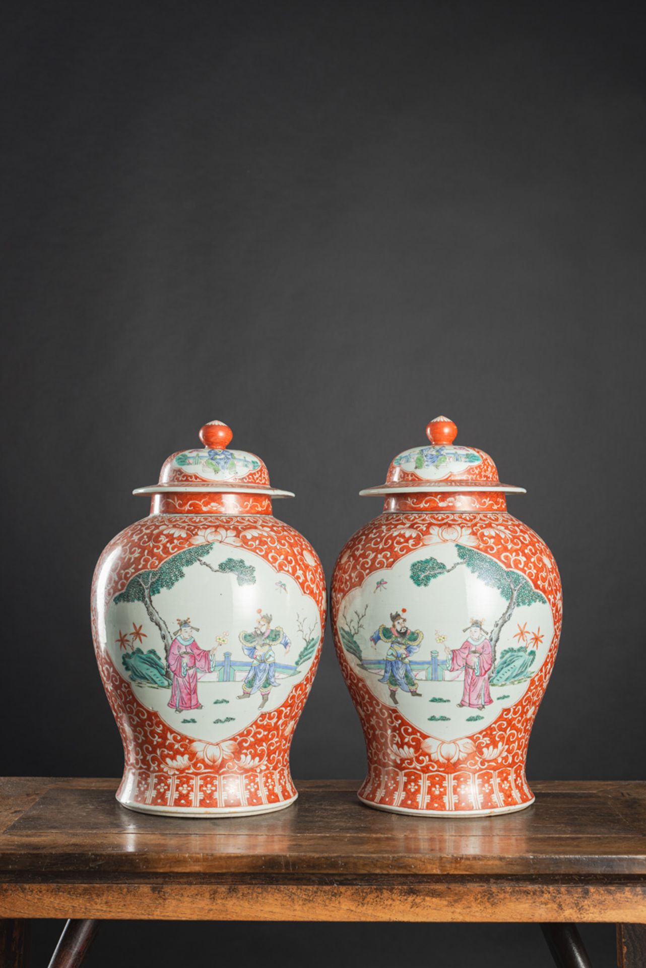 A PAIR OF IRON-RED-GROUND 'FAMILLE ROSE' FIGURAL RESERVES PORCELAIN VASES AND COVERS - Image 3 of 5