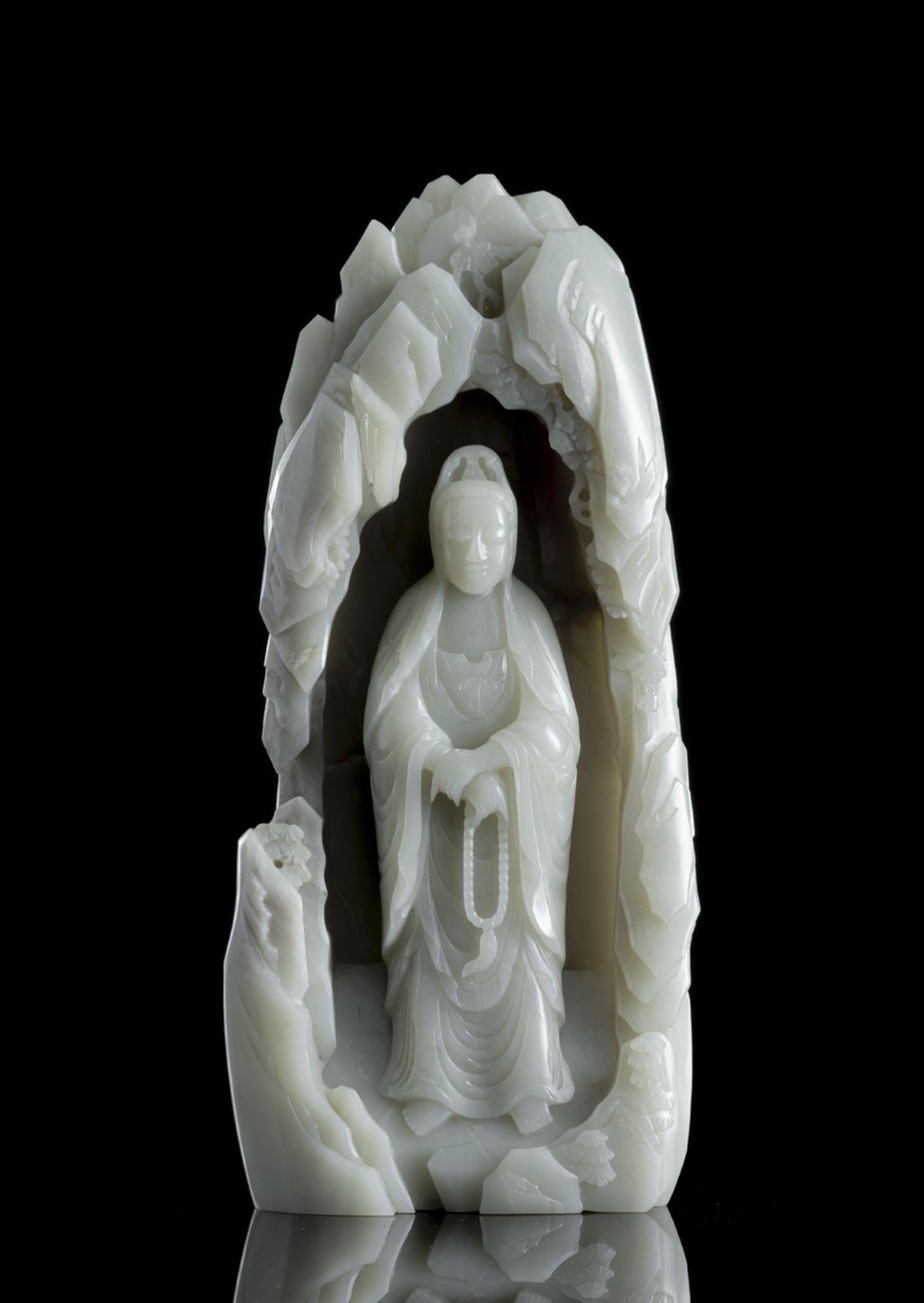 A RARE PALE CELADON JADE FIGURE OF GUANYIN IN A GROTTO