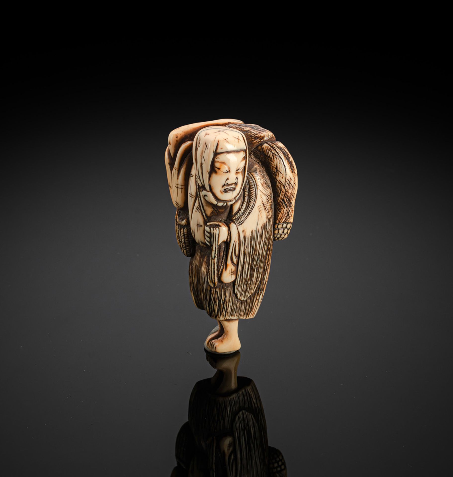 A CARVED IVORY NETSUKE OF A STANDING FARMER