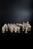 Gruppe von 26 teils glasierten und kalt bemalten Tonfiguren einer Prozession mit Reiterfiguren und