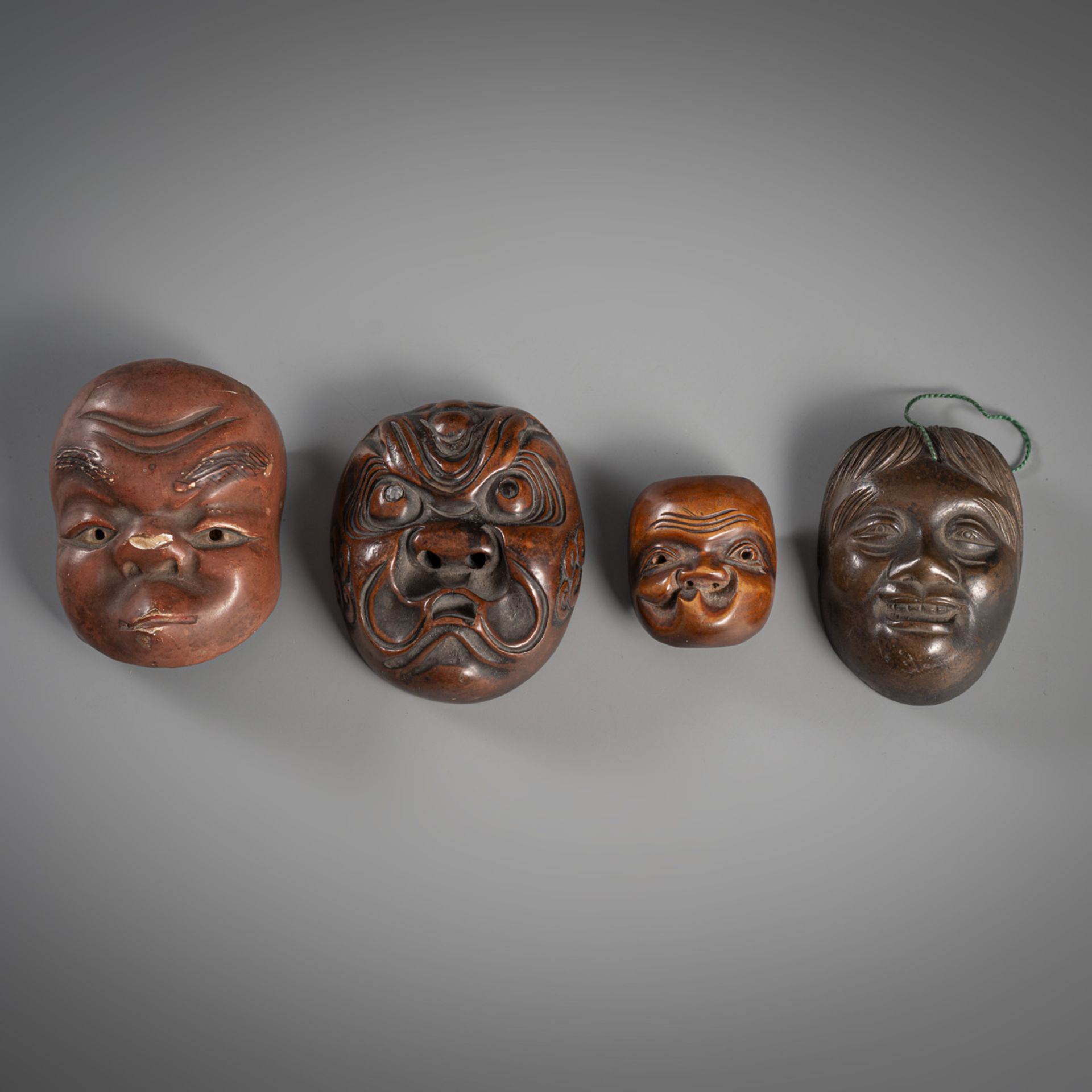 FOUR SMALL MASKS AMONG OTHERS TWO NETSUKE MADE OF WOOD, BRONZE AND CERAMIC
