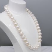 An 18 inch string of white freshwater cultured pearls with a 9ct rose gold ball clasp
