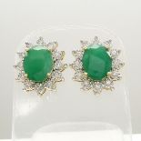 Emerald and diamond oval cluster earrings with butterfly backs, in yellow gold.