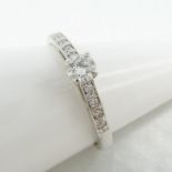 18k white gold diamond solitaire-style ring, with further diamonds set to the shoulders.