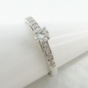 18k white gold diamond solitaire-style ring, with further diamonds set to the shoulders.