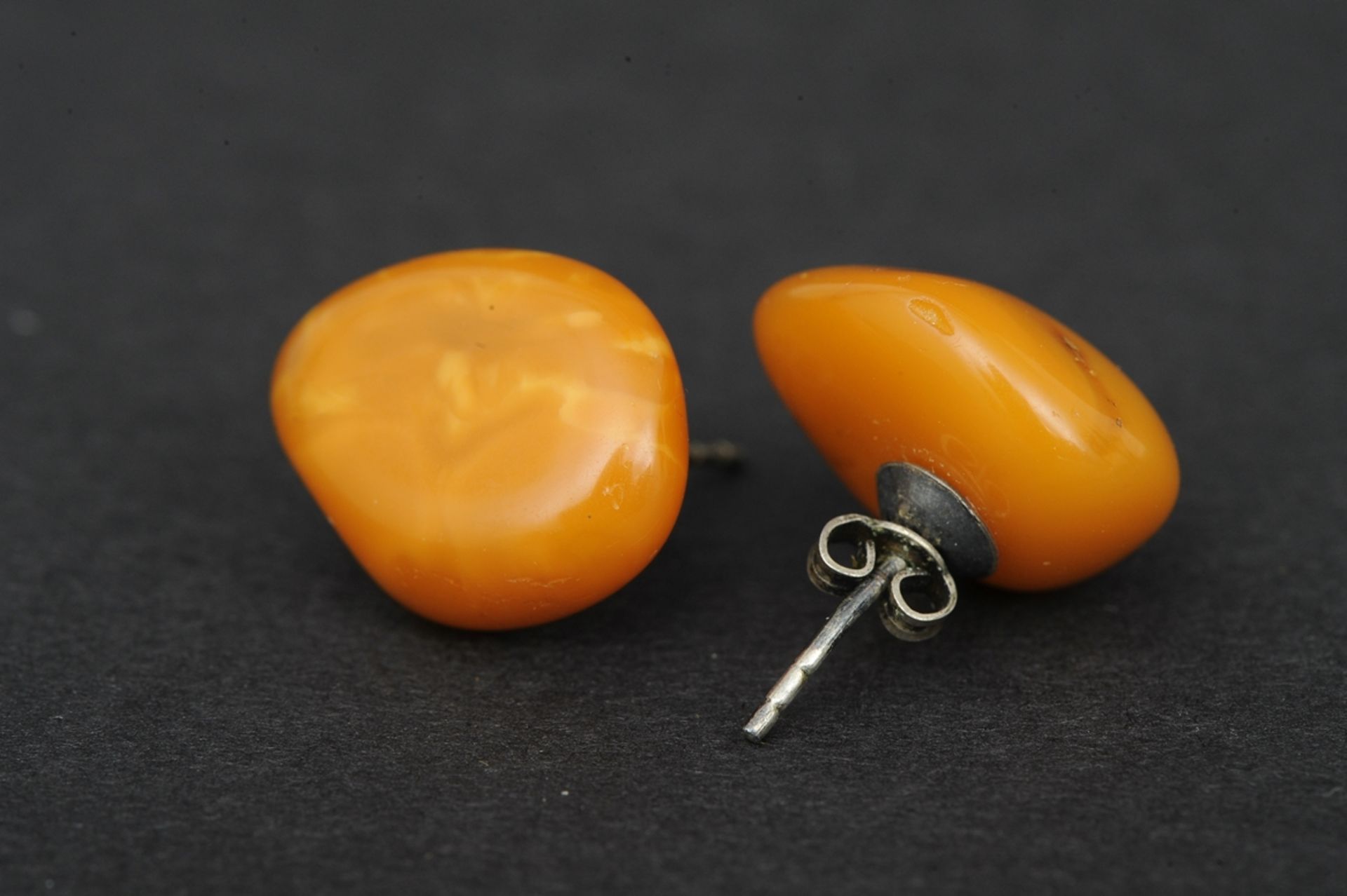 Paar Bernstein-Ohrstecker in Orange-Tönen, silberne Fassung, der Bernstein in Form und Farbe leicht